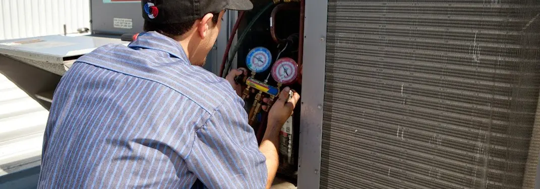 HVAC technician servicing a condenser unit in Eagle Mountain